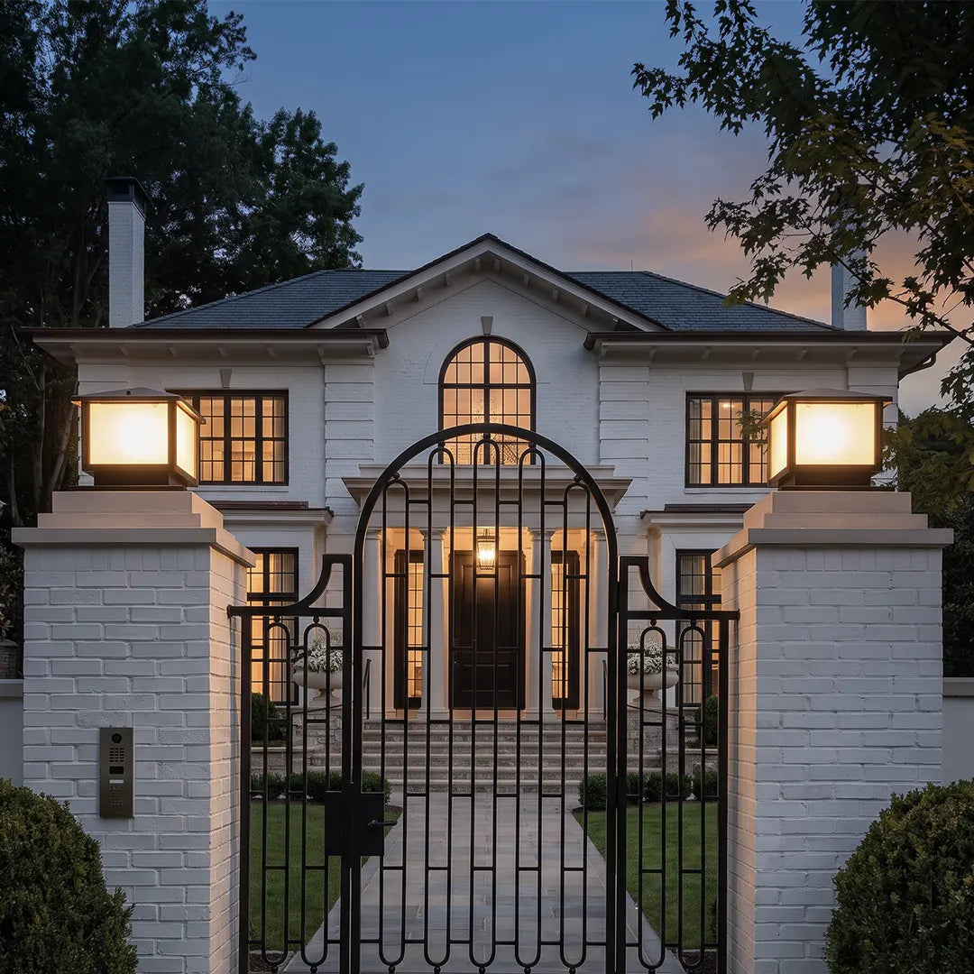 Modern outdoor pillar lights accenting front gate pillars and a luxury home entrance in an elegant nighttime setting.