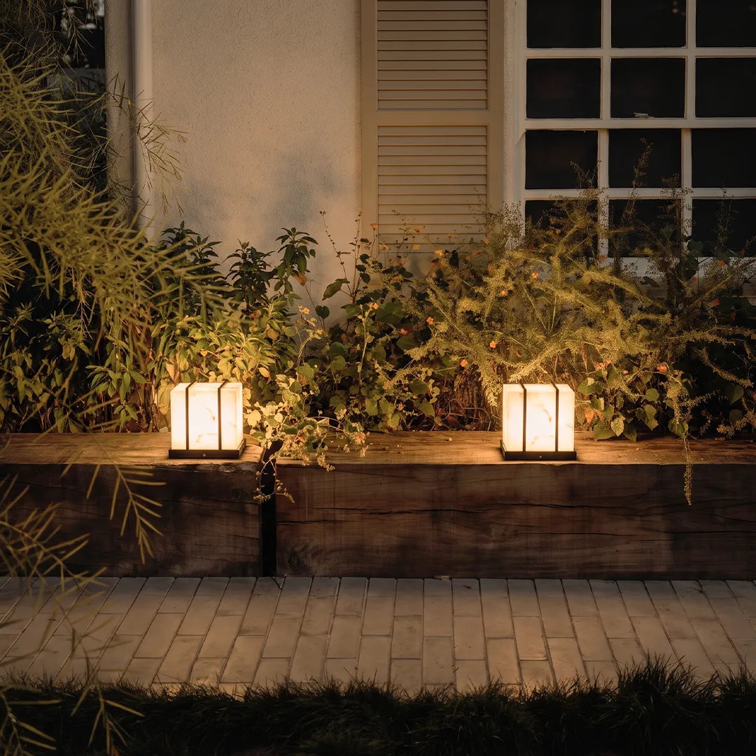 Modern outdoor pillar lights illuminating raised garden planter and flowers