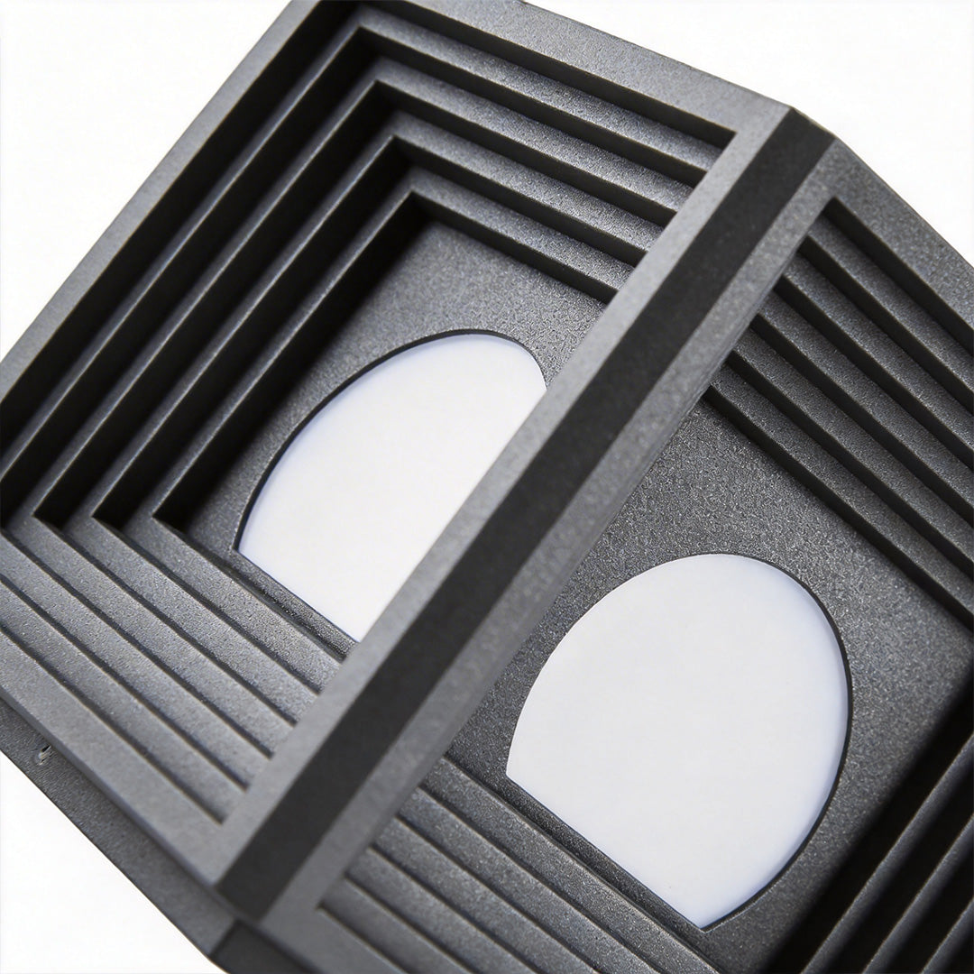 Modern outdoor pillar lights with a sleek design, providing soft illumination near a fence.