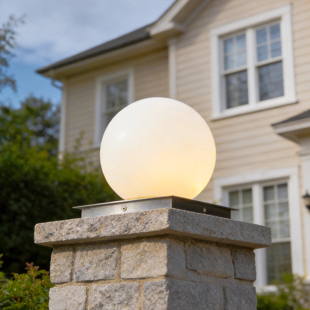 Modern outdoor pillar lights set on a stone pillar, highlighting a spherical globe design in a residential yard.