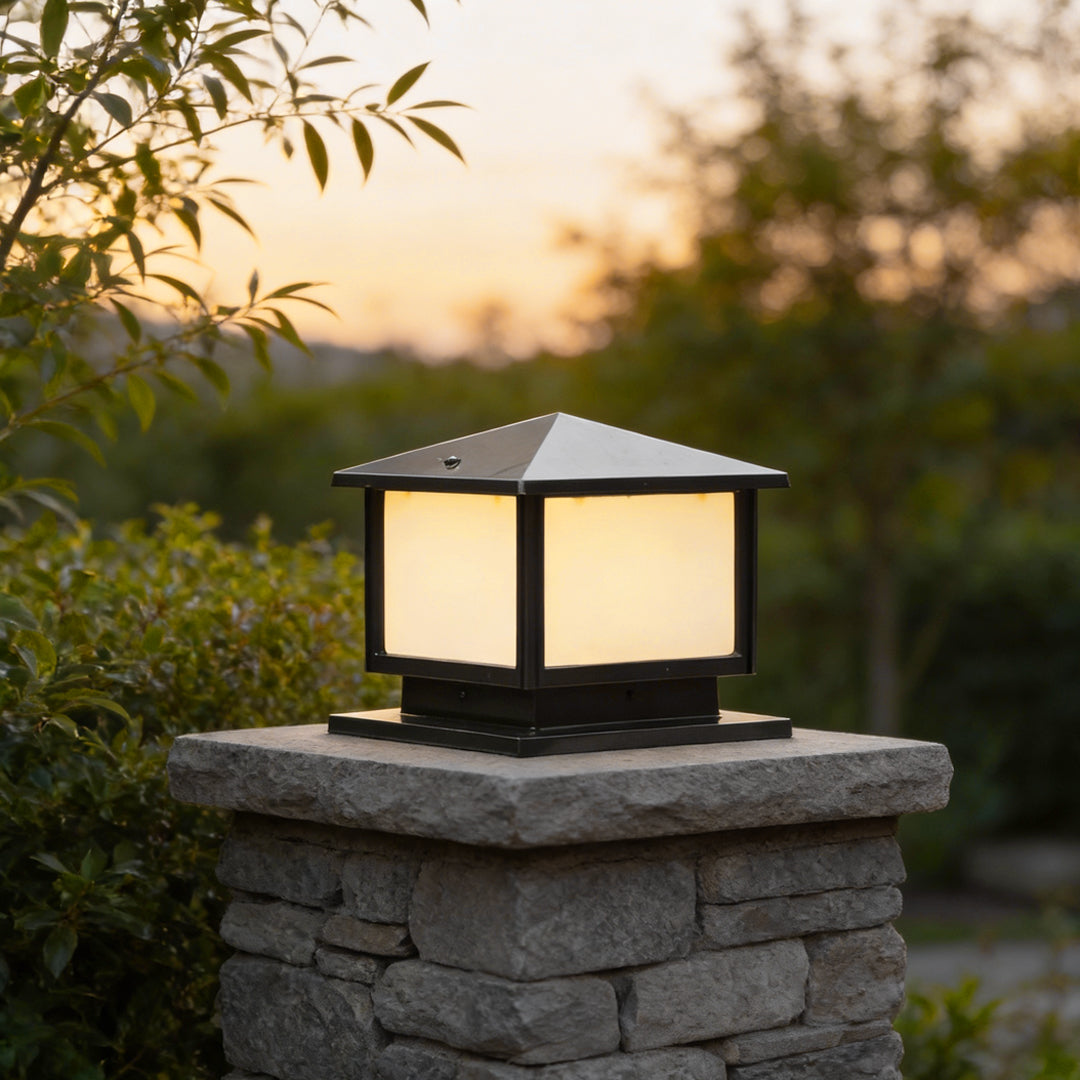 Modern outdoor pillar lights mounted on a stone column, featuring a square black frame and soft warm glow for garden entrances.