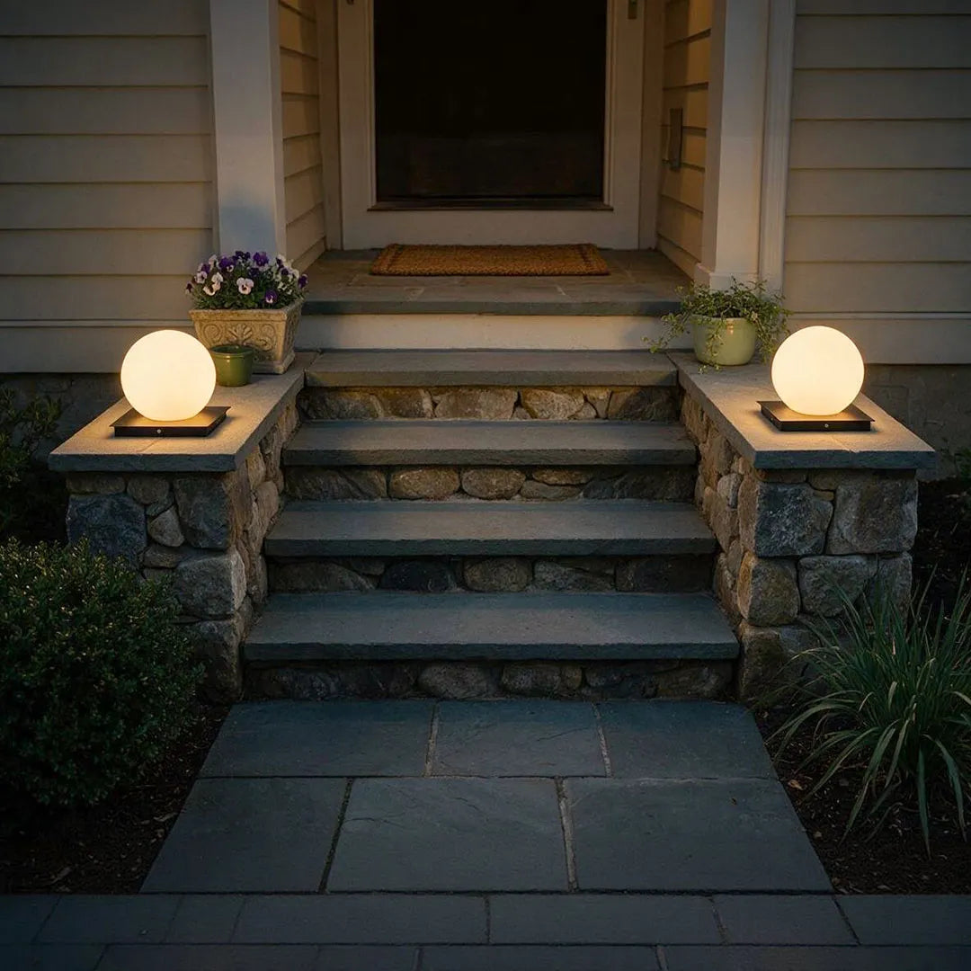 Modern outdoor pillar lights placed on stone entry steps, creating a warm and welcoming front porch glow.