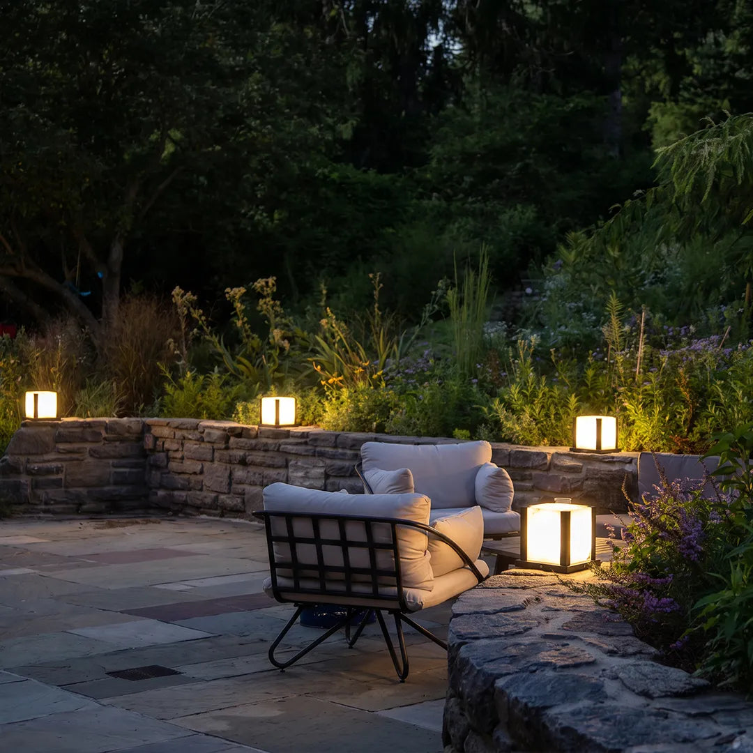 Modern outdoor pillar lights illuminating stone garden patio and lounge seating