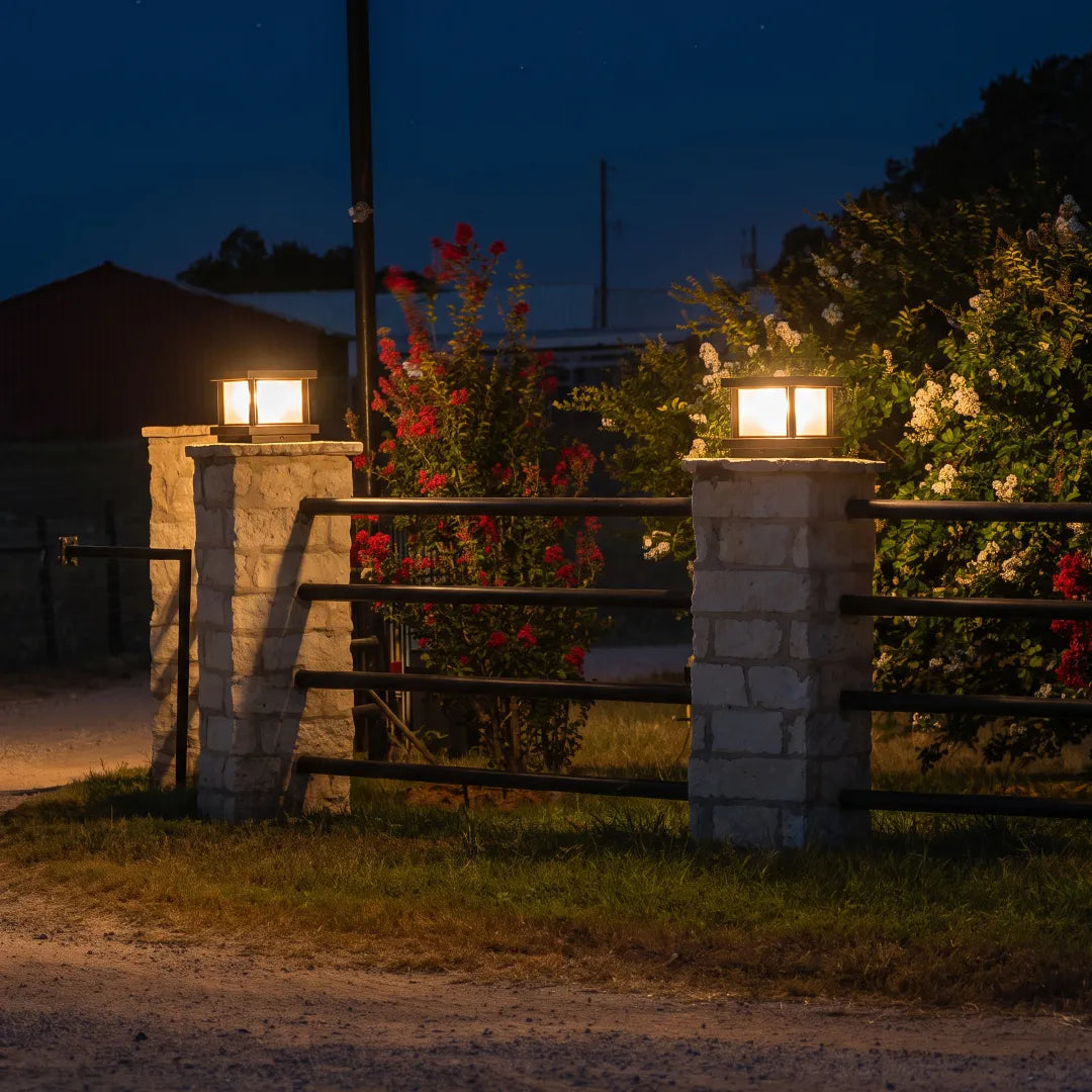 Modern outdoor pillar lights with warm glow on stone gate columns at night