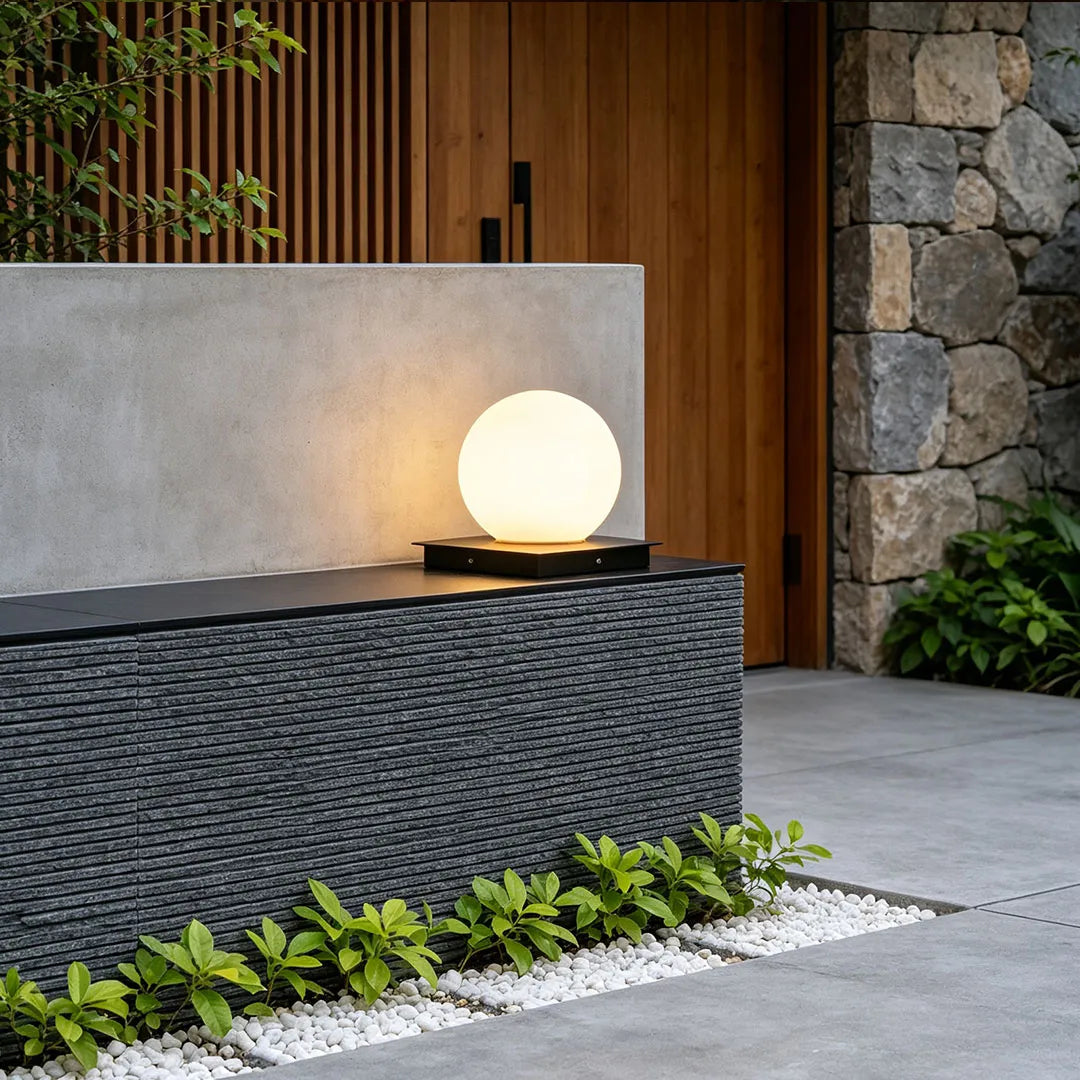 Modern outdoor pillar lights displayed on a textured stone pedestal near a contemporary front door.