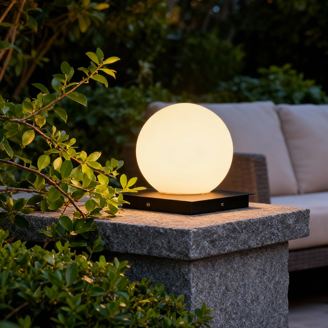 Modern outdoor pillar lights placed on a stone post beside garden foliage, creating a soft ambient evening glow.