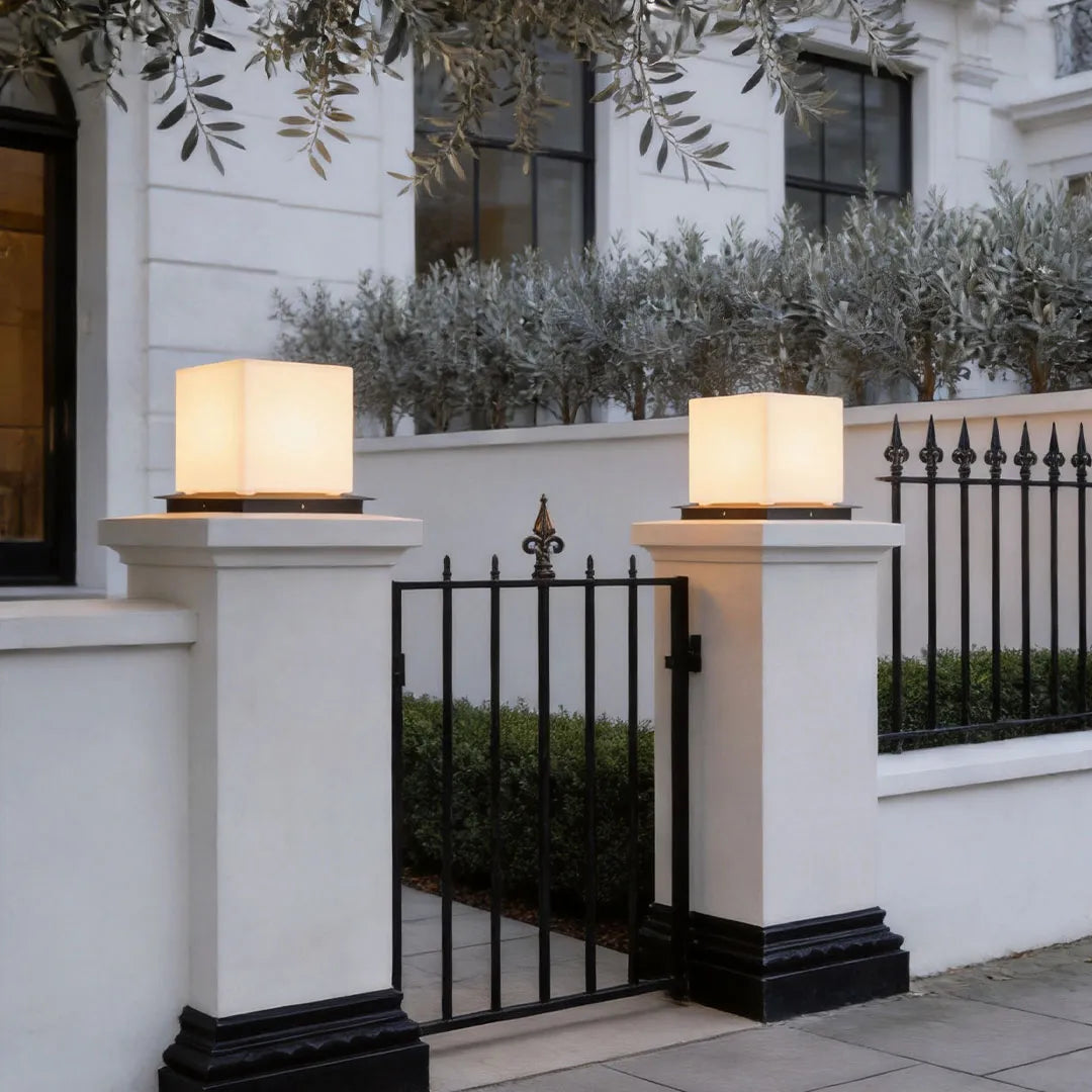 Modern outdoor pillar lights mounted on white gate posts, bringing elegant lighting to a refined exterior entrance.