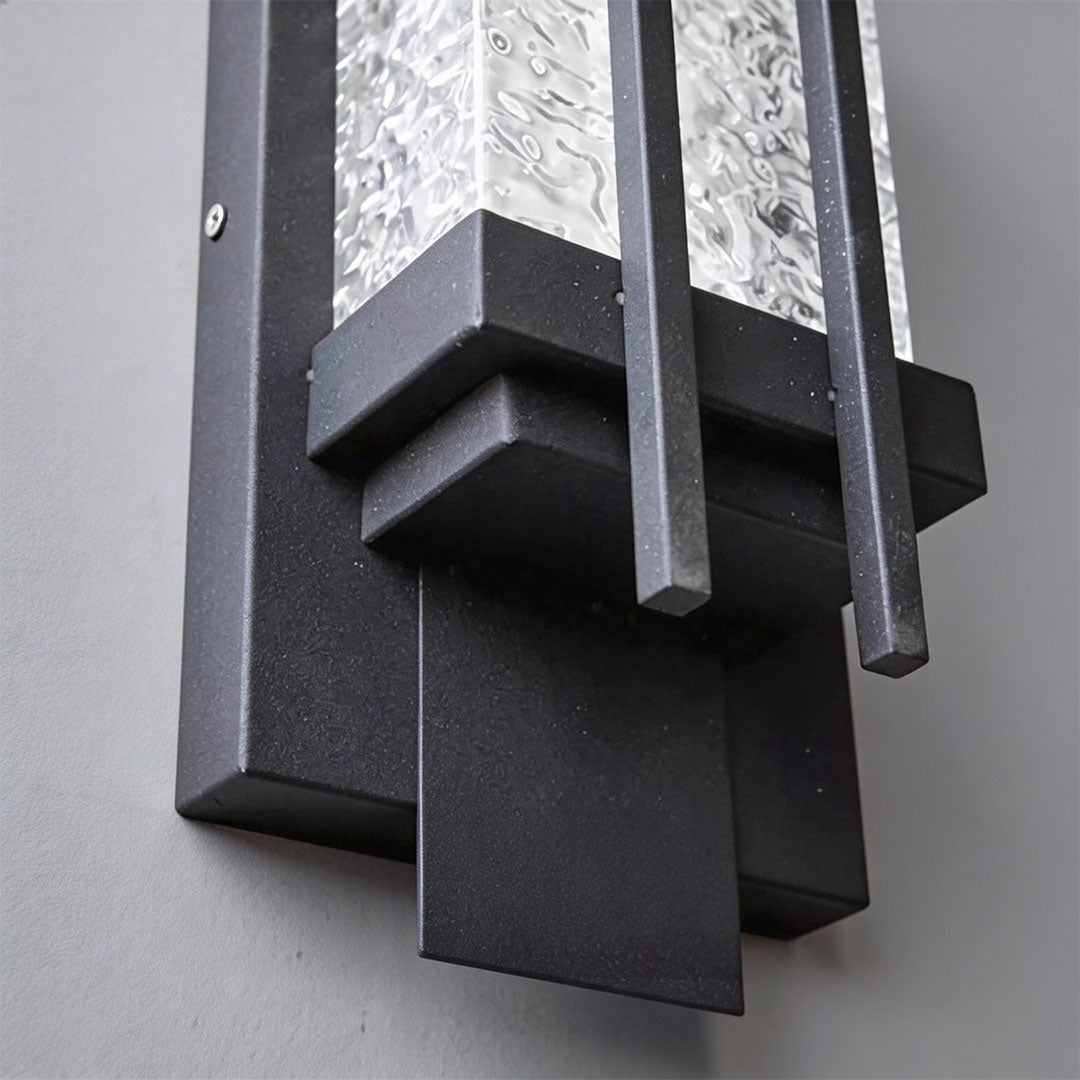 Close-up of modern outdoor sconce lighting showcasing its glass panel and warm light.