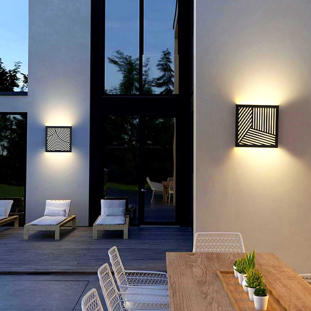 Contemporary outdoor entrance illuminated by modern outdoor sconces black with artistic cutout lighting effect.