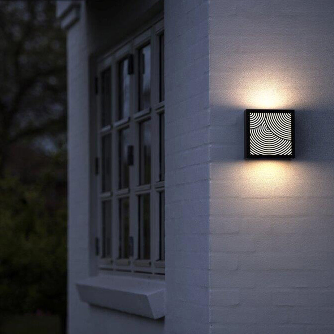 Simple exterior wall with square modern outdoor sconces black emitting soft geometric patterned light.
