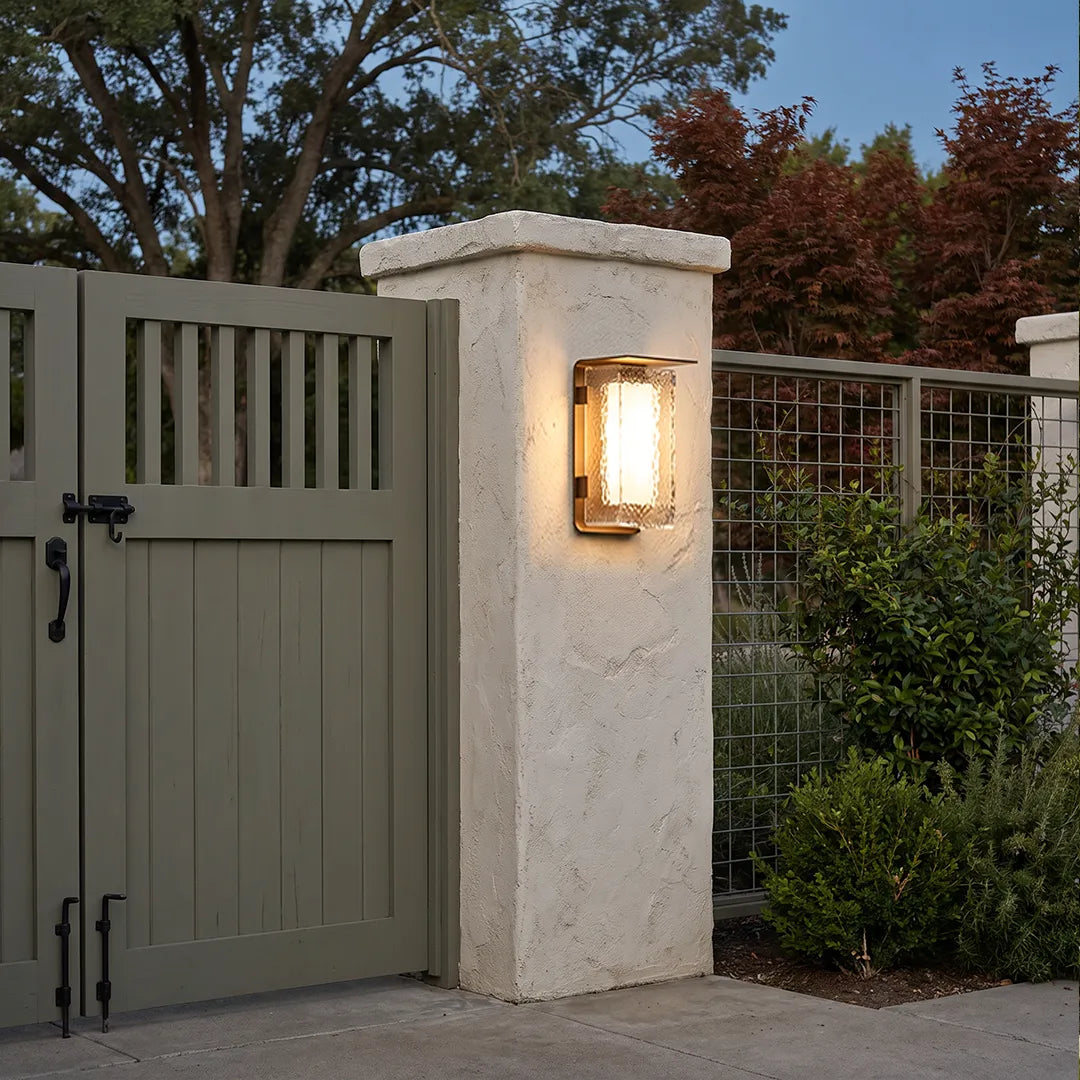 Modern outdoor solar wall lights mounted on gate pillars beside a green garden gate.