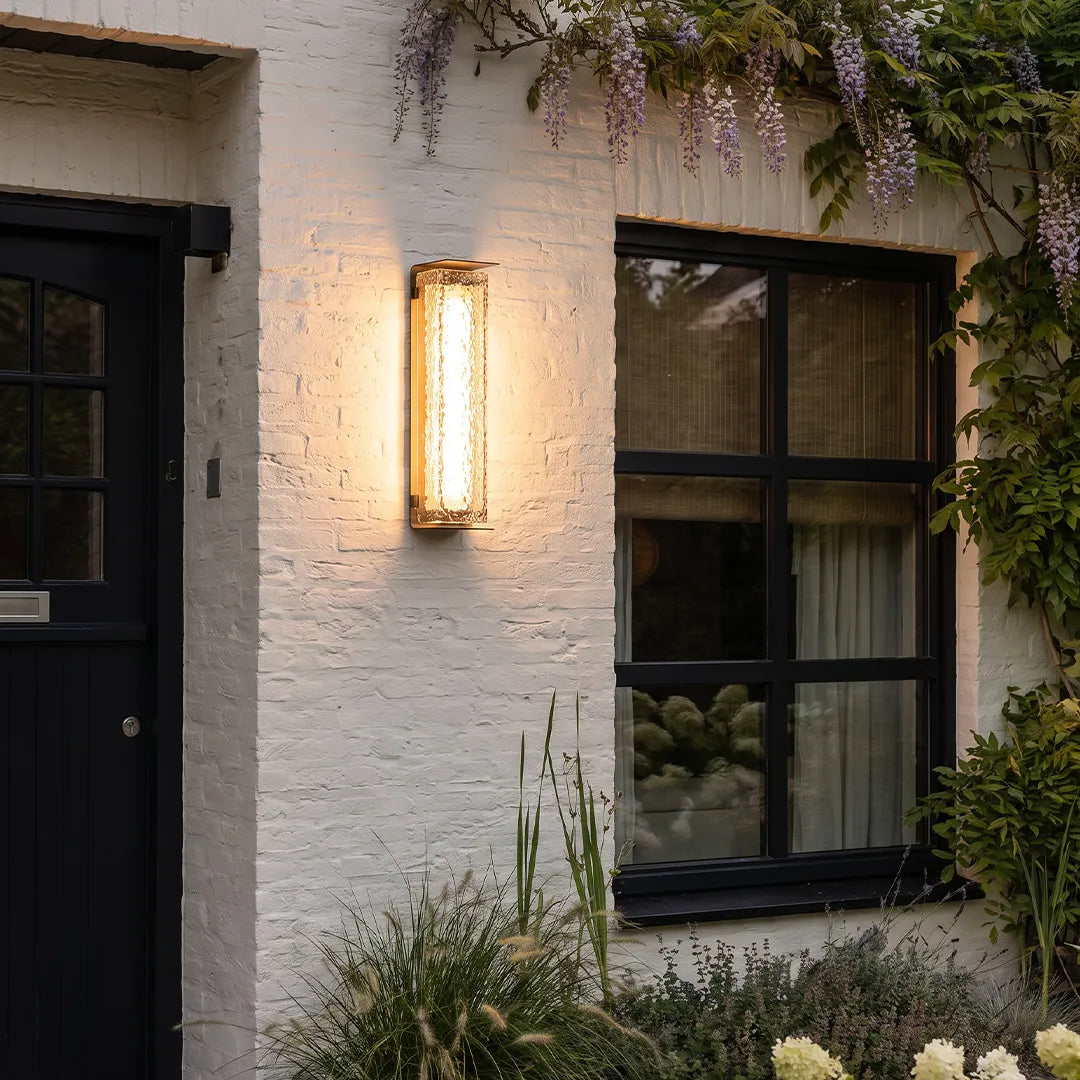 Modern outdoor solar wall lights mounted on a white brick wall beside a black framed window.
