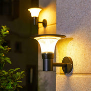 Modern outdoor solar wall sconce with a 'halo' solar panel, casting a warm yellow glow on a textured wall.
