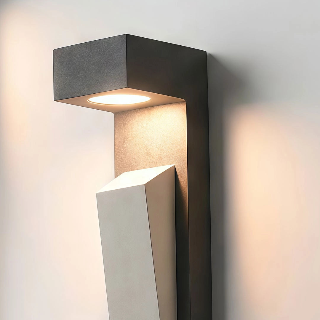 Modern outdoor wall light shown in detail with a geometric stone body and warm LED glow.