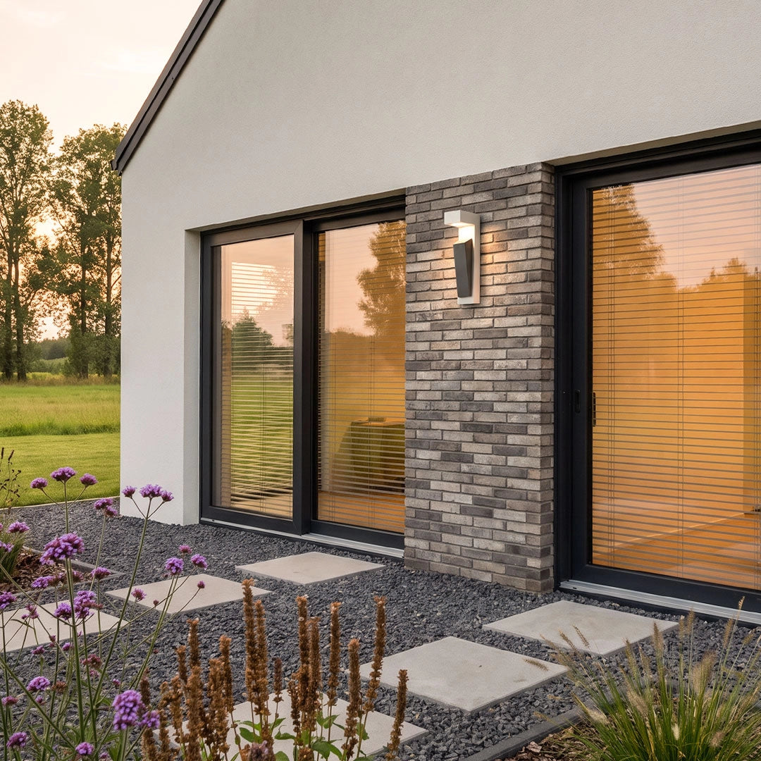 Modern outdoor wall light mounted on a stone accent wall beside large patio doors.