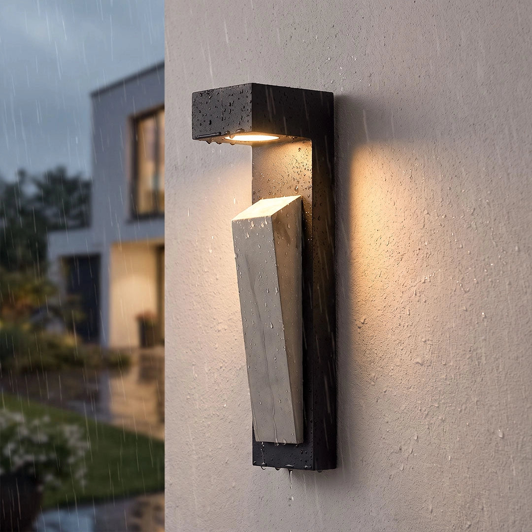 Modern outdoor wall light in a close-up view with a textured stone design and warm downward glow.