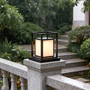 Modern outdoor wall pillar light installed on stone railing, creating warm ambient garden lighting.