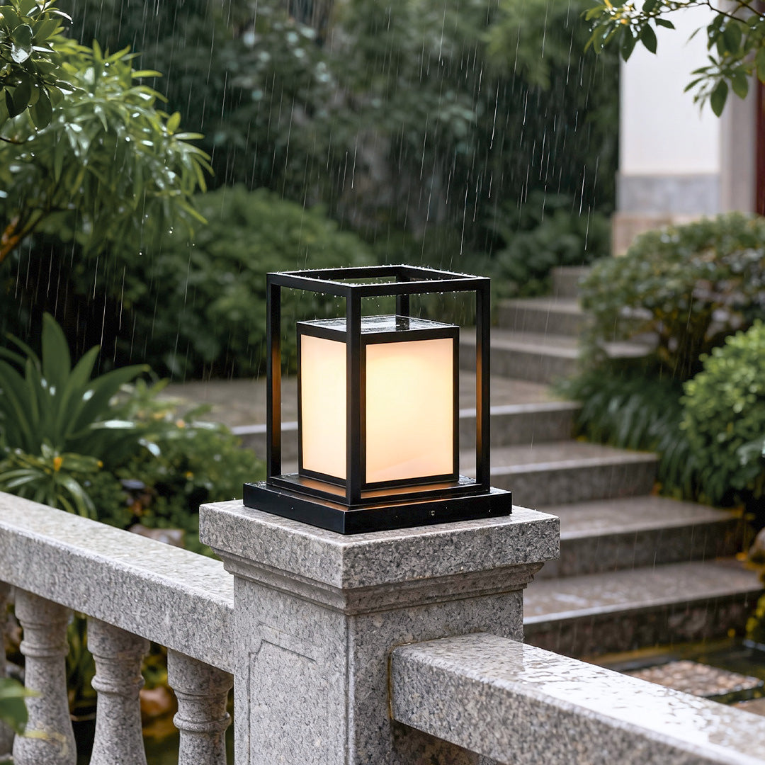 Modern outdoor wall pillar lights installed on stone railing, creating warm ambient garden lighting.