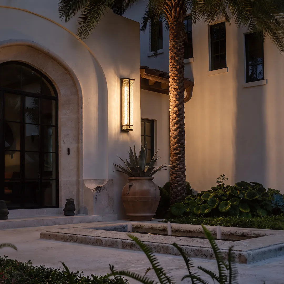 Modern outdoor wall sconce with warm glow beside arched home entrance