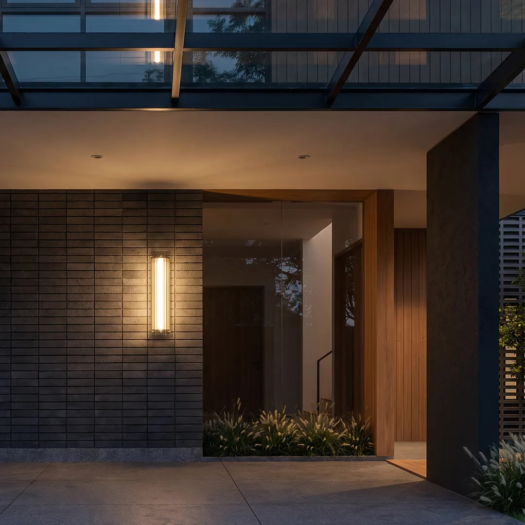 Modern outdoor wall sconce illuminating covered home entrance at dusk