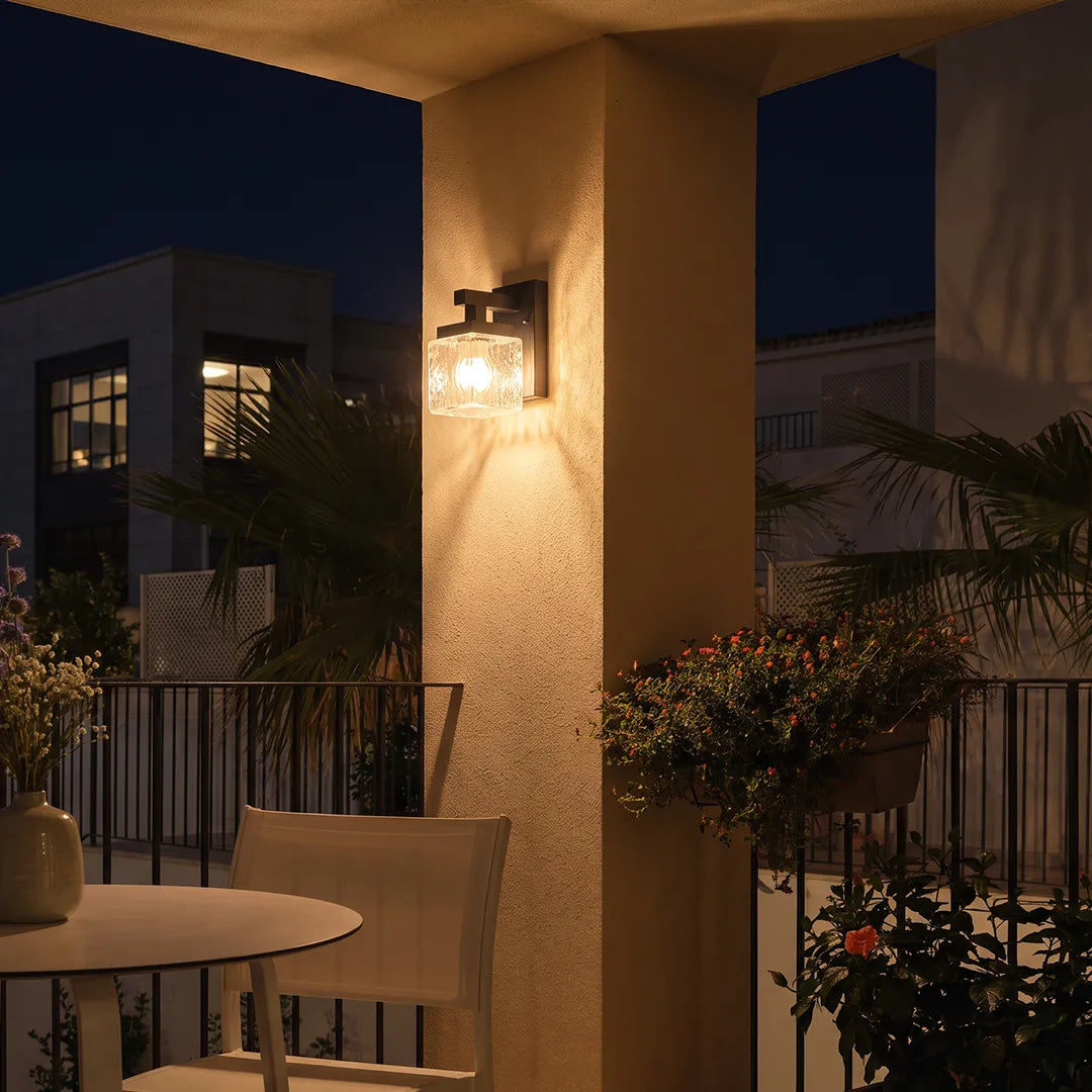 Modern outdoor wall sconce illuminating covered patio and outdoor dining area