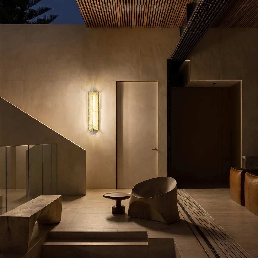Modern outdoor wall sconce with warm glow beside contemporary patio lounge