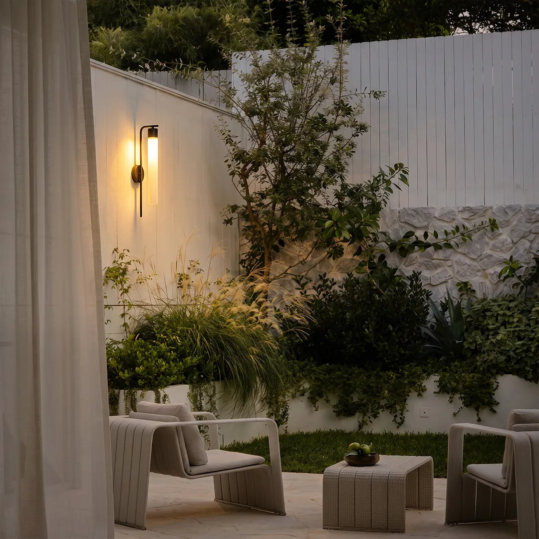 Modern outdoor wall sconce illuminating garden patio and lounge seating