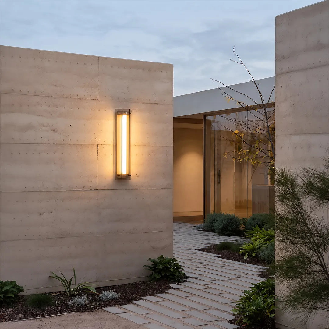 Modern outdoor wall sconce illuminating concrete garden wall and walkway