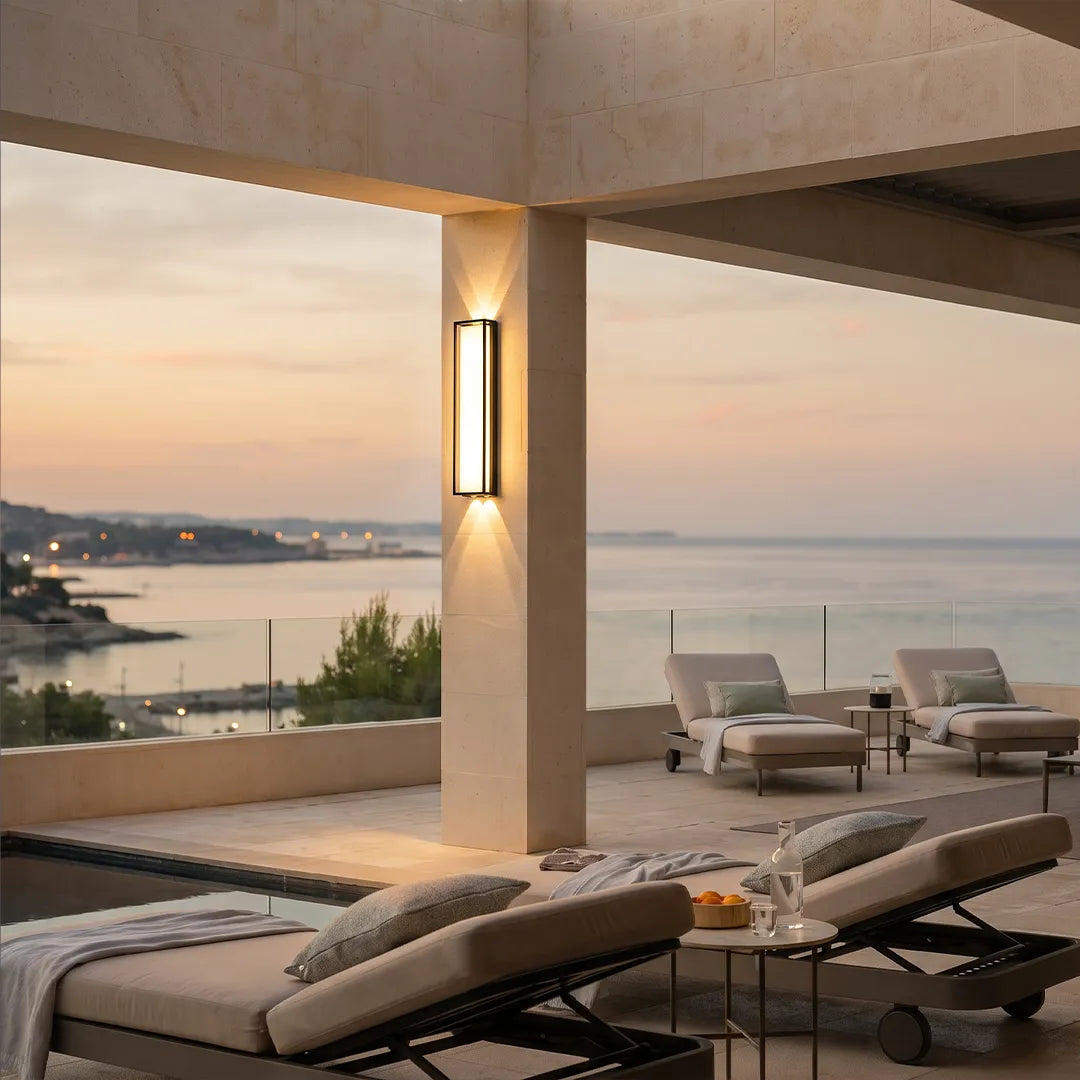 Modern outdoor wall sconce with warm glow beside ocean view terrace