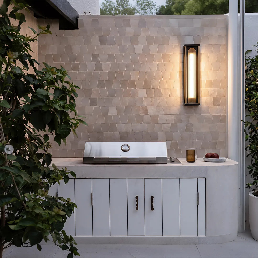 Modern outdoor wall sconce with warm glow above outdoor kitchen counter