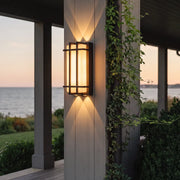 Modern outdoor wall sconce with black frame and warm glow on patio column