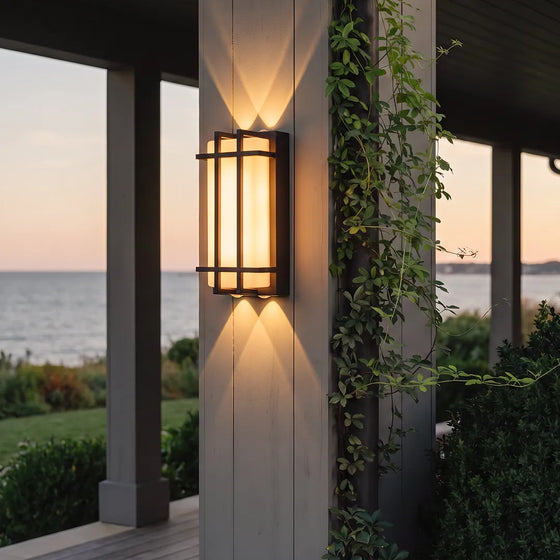Modern outdoor wall sconce with black frame and warm glow on patio column