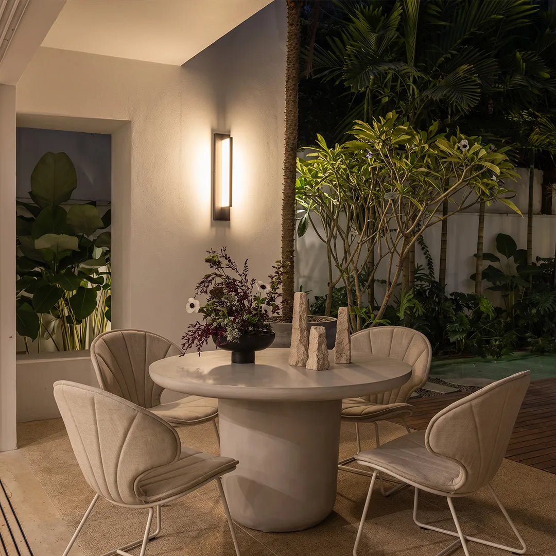 Modern outdoor wall sconce illuminating covered patio dining area