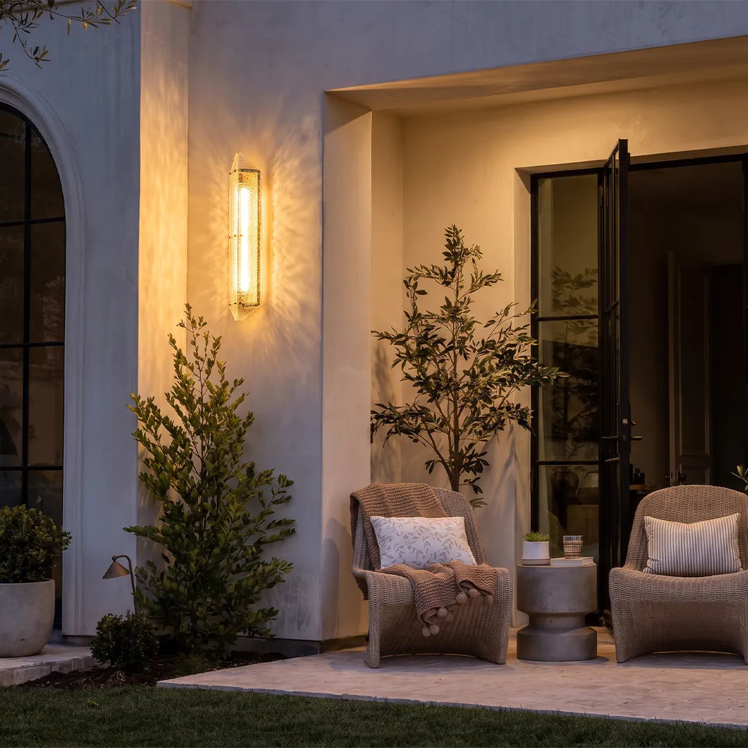 Modern outdoor wall sconce with warm glow beside covered patio entrance