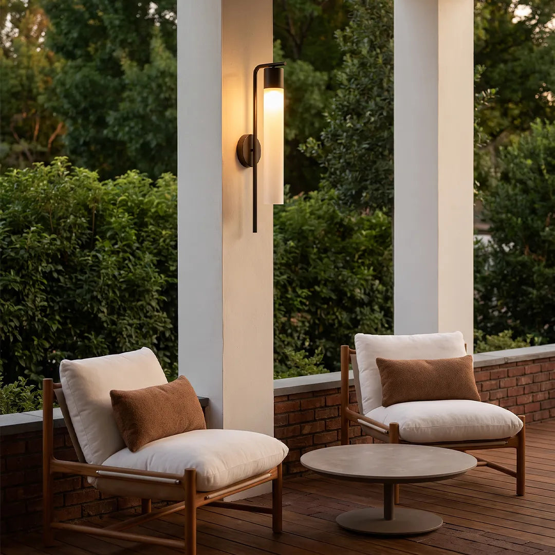 Modern outdoor wall sconce on porch column beside outdoor lounge chairs