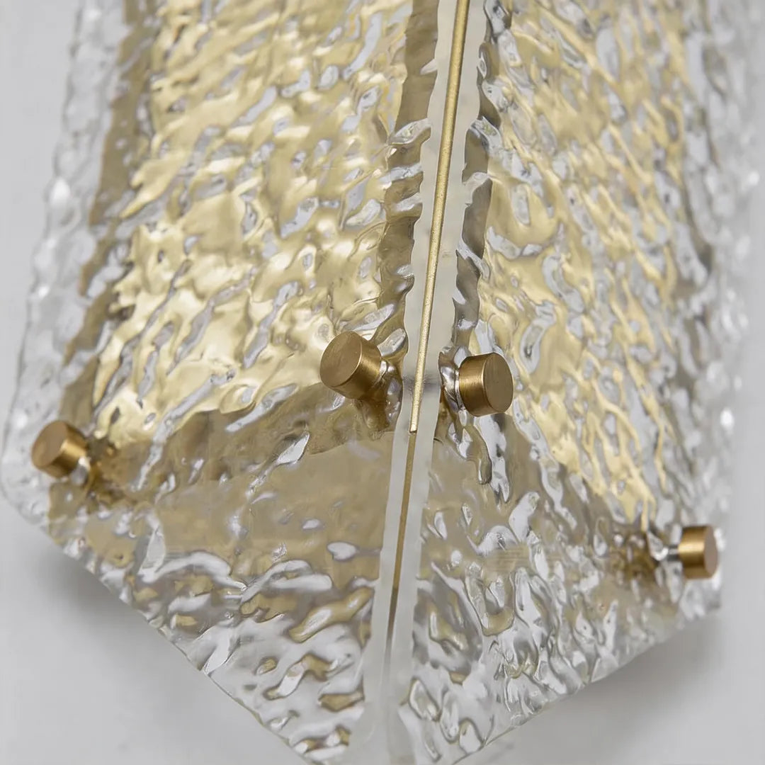 Modern outdoor wall sconce with clear textured glass and gold mounting details