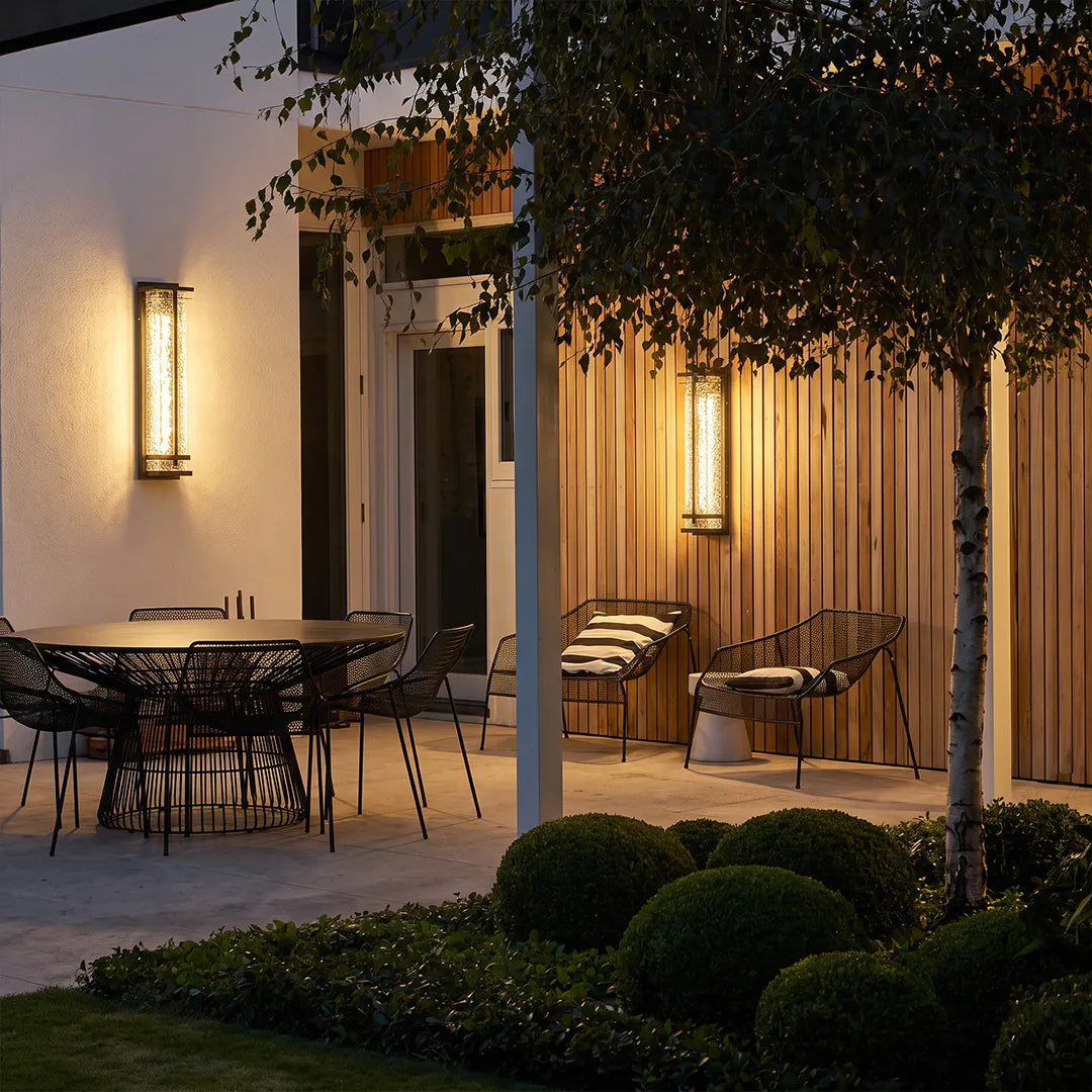 Modern outdoor wall sconces illuminating covered garden patio and dining area