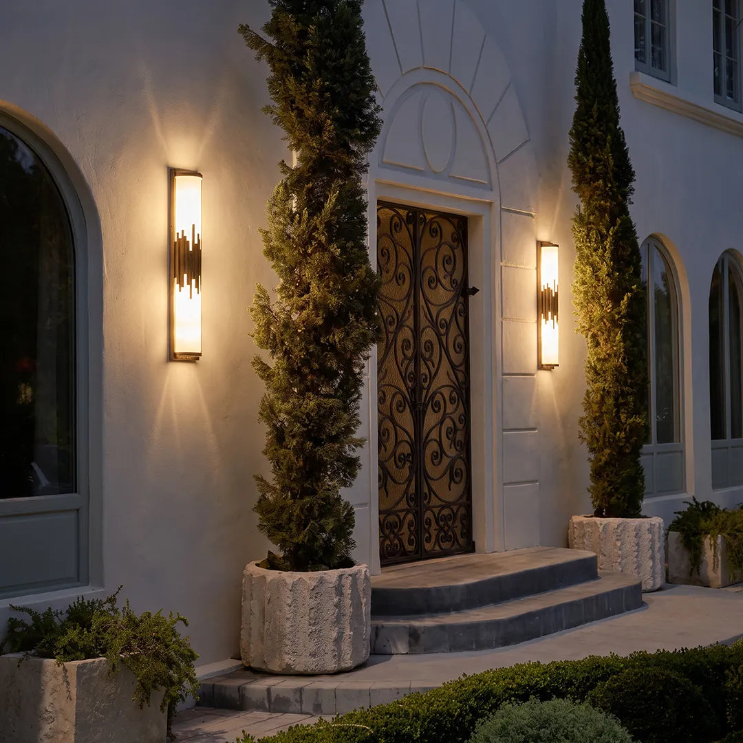 Modern outdoor wall sconces with warm glow beside elegant front door