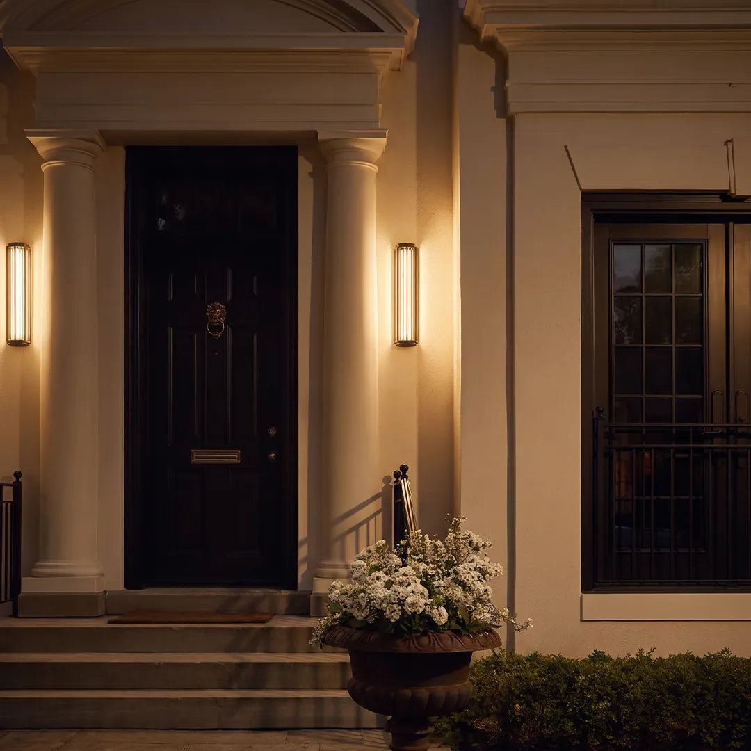 Modern outdoor wall sconces with warm lighting beside elegant front door