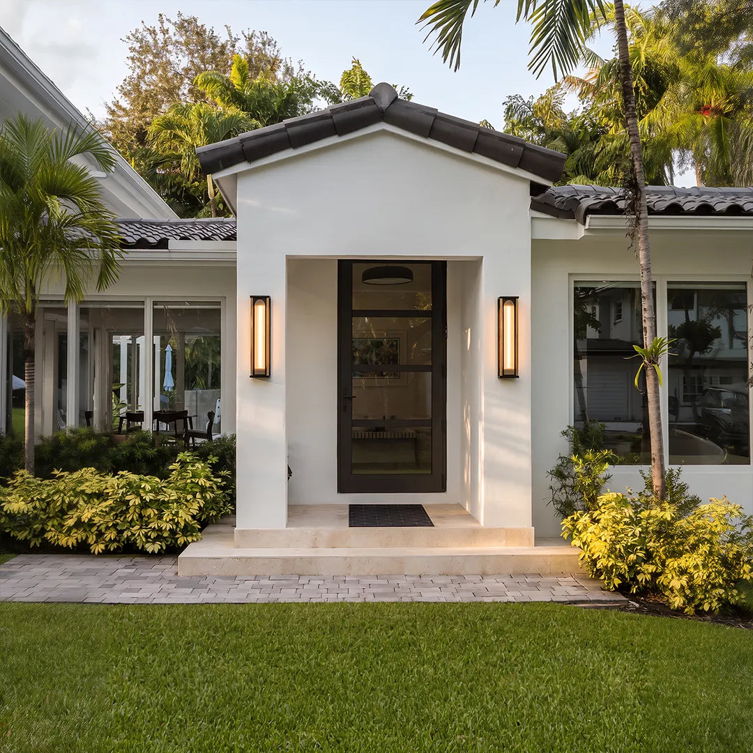 Modern outdoor wall sconces illuminating front door and landscaped garden