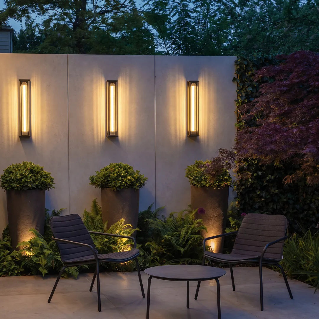 Modern outdoor wall sconces with warm glow beside garden patio seating