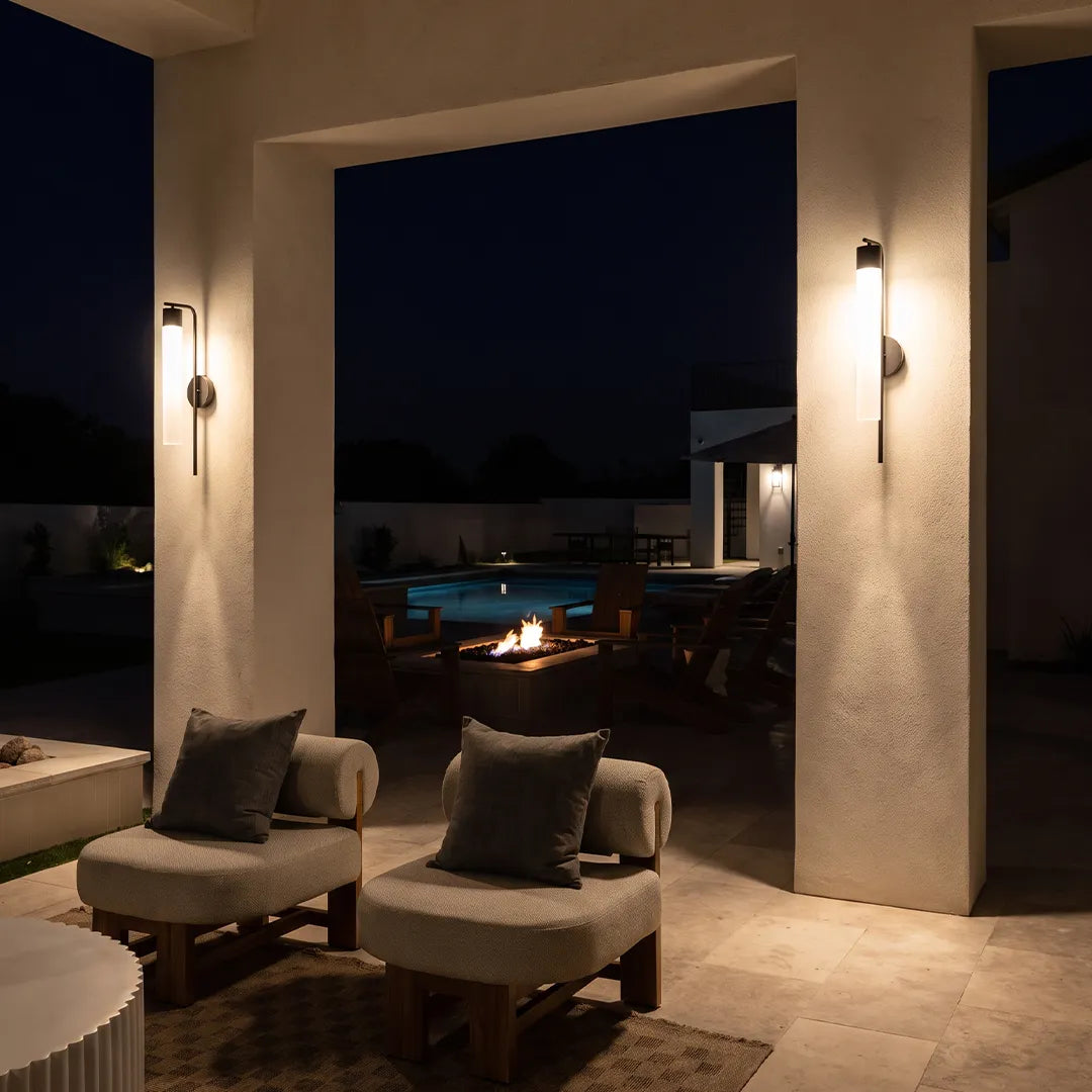 Modern outdoor wall sconces illuminating covered patio lounge at night