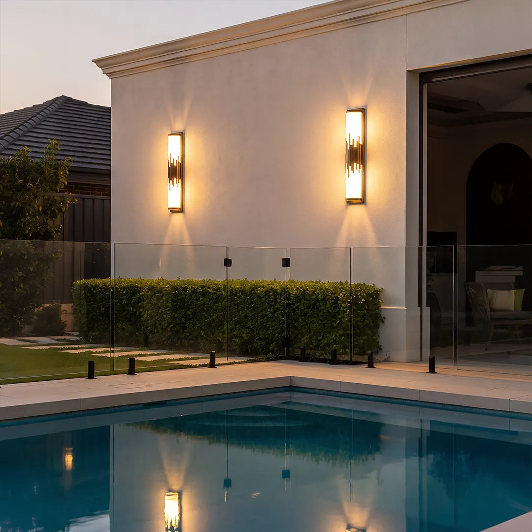 Modern outdoor wall sconces illuminating exterior wall beside swimming pool