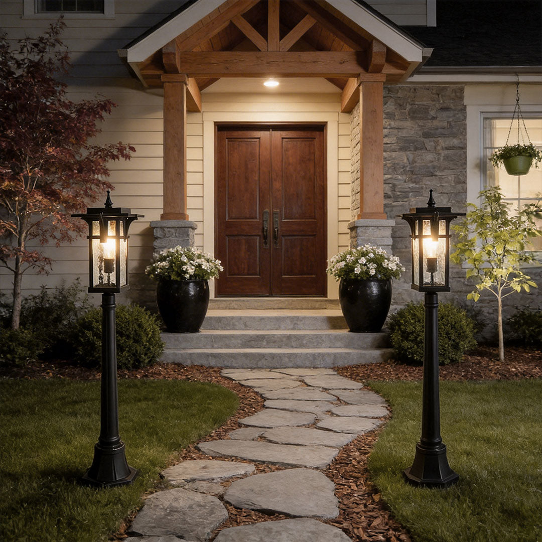 Modern path light with black metal frame and glass panels at the entrance of a residential home.