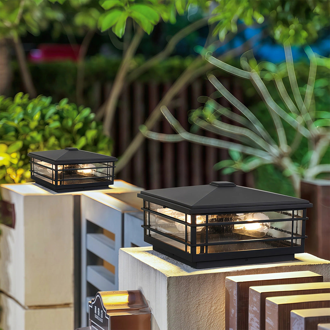 Modern pillar lights outdoor installation on white post railing with lush tropical plants background