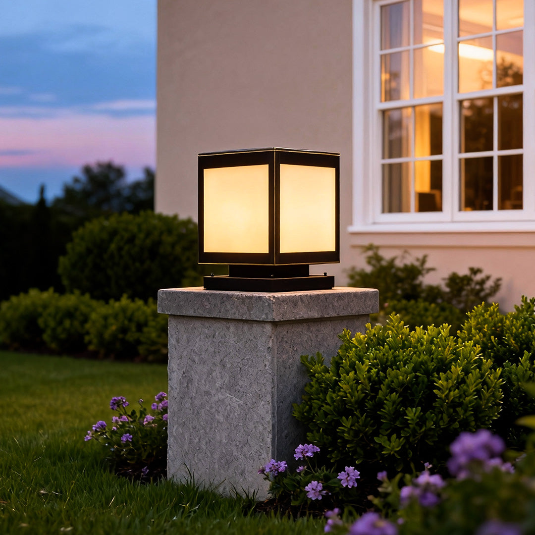 Modern pillar solar light illuminating a garden pathway beside a house during evening hours.