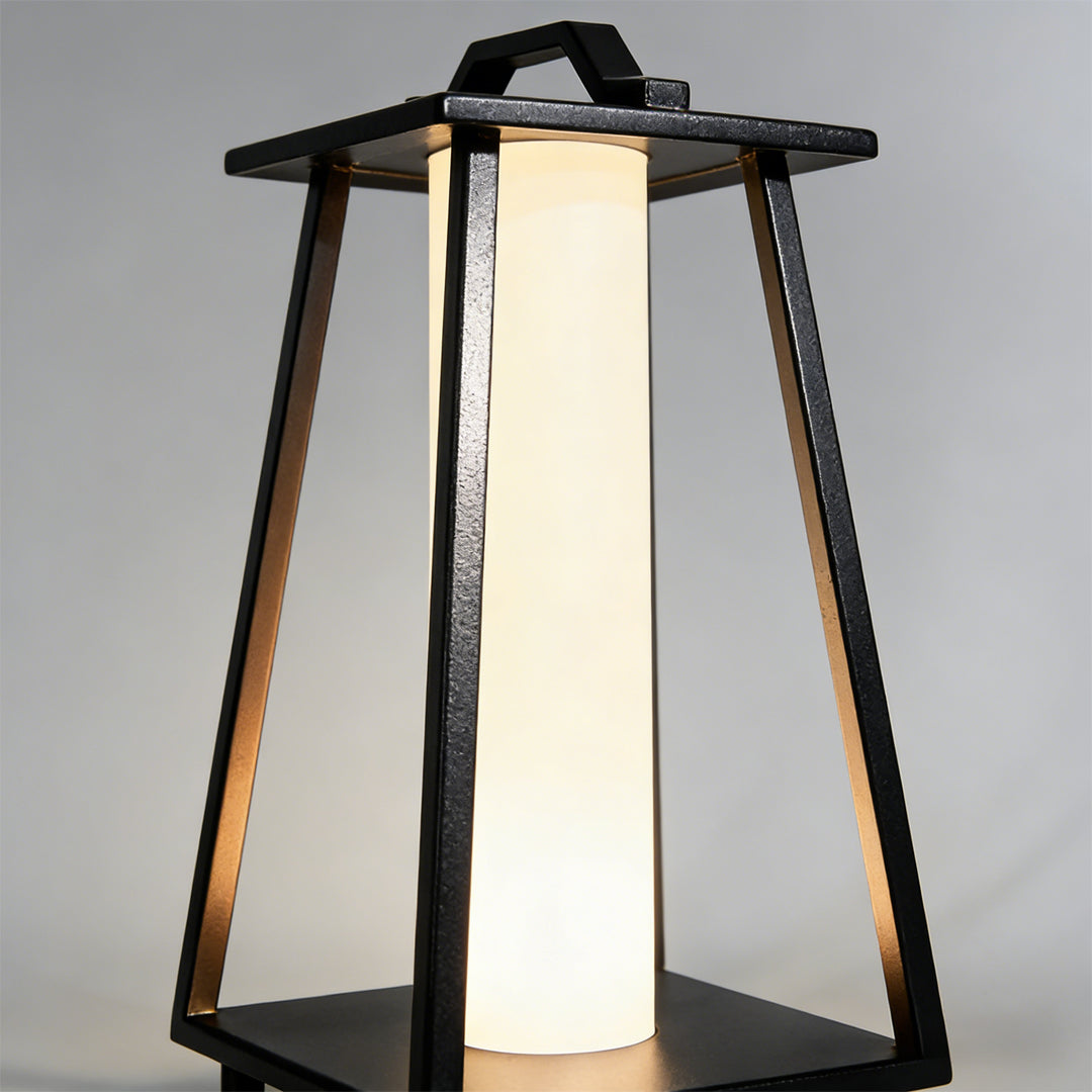 Modern portable outdoor lantern angled studio view highlighting textured metal legs and handle.