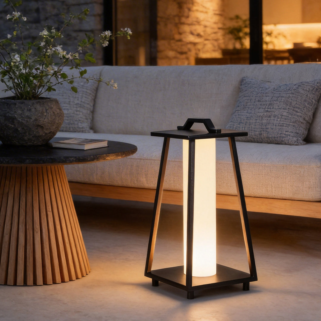 Modern portable outdoor lantern with warm glow positioned next to outdoor seating in a contemporary terrace.