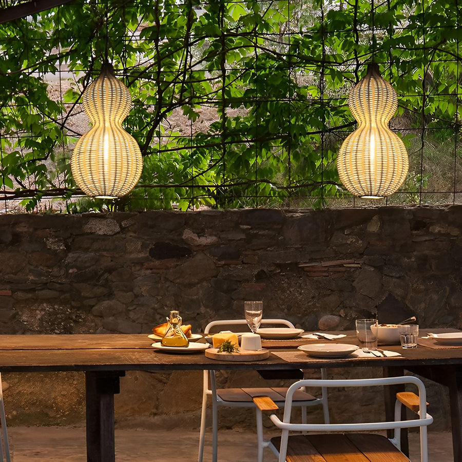 Modern rattan pendant light suspended above an outdoor dining table, blending natural materials with modern garden decor.