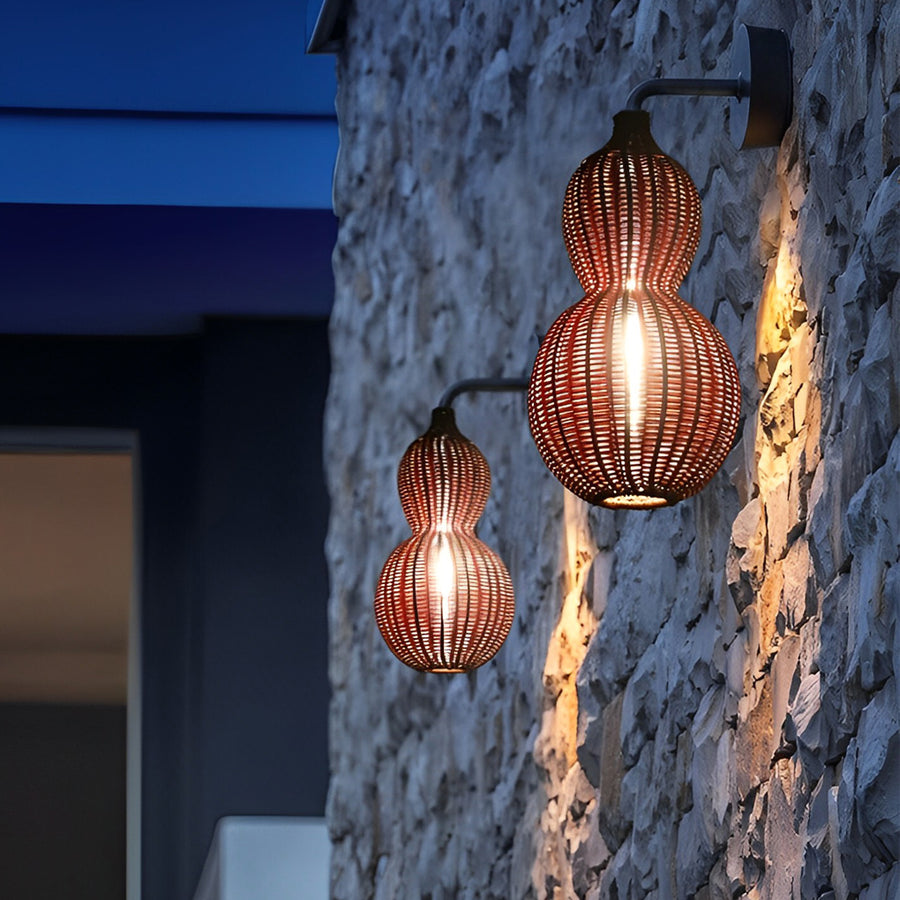 Modern rattan pendant light displayed against a stone wall exterior, highlighting textured surfaces with warm light.